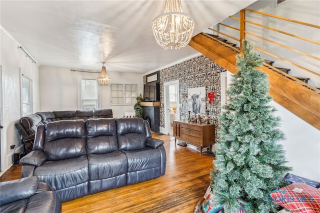 living room featuring a chandelier, wood-type flooring, plenty of natural light, and crown molding