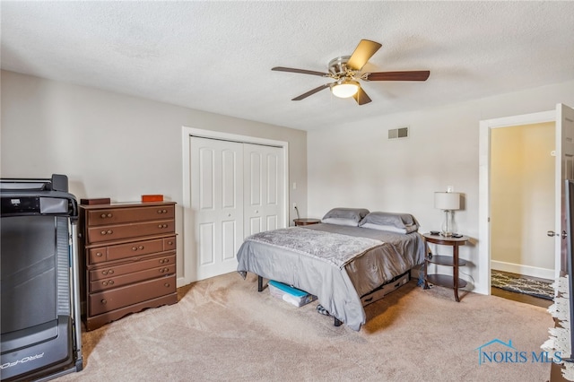 bedroom with ceiling fan, a closet, light colored carpet, and a textured ceiling