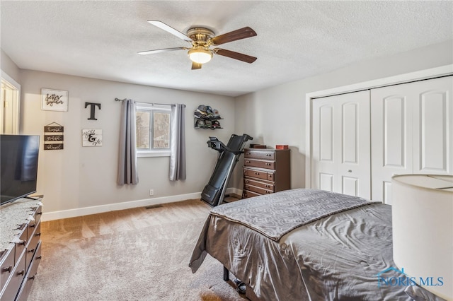 carpeted bedroom with ceiling fan, a textured ceiling, and a closet