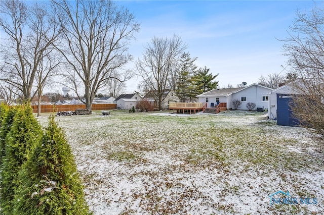 snowy yard with a storage unit and a deck