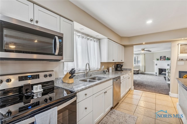 kitchen with white cabinets, appliances with stainless steel finishes, light stone countertops, and sink