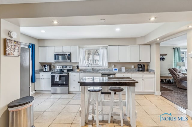 kitchen featuring stainless steel appliances, white cabinetry, plenty of natural light, and sink