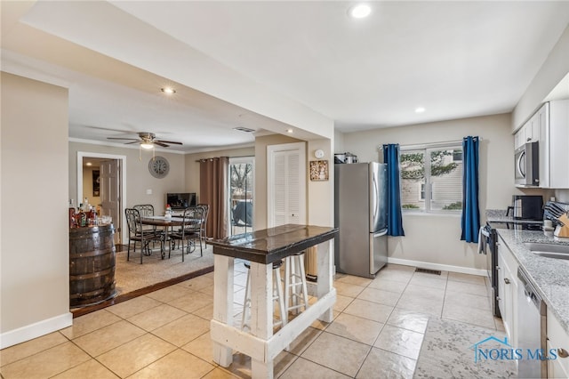 kitchen featuring appliances with stainless steel finishes, white cabinetry, plenty of natural light, and light stone counters