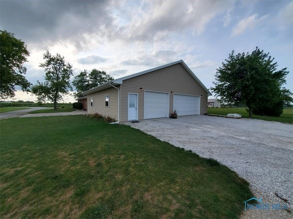 view of side of property featuring a garage and a lawn