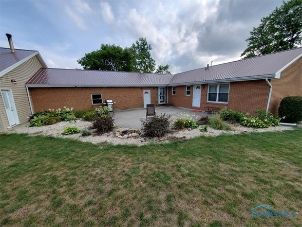 back of property featuring a lawn and a patio area