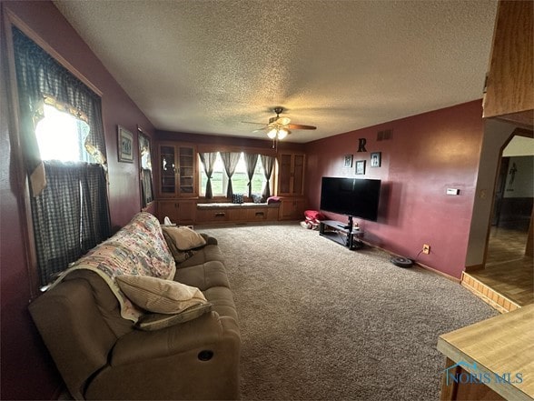 carpeted living room featuring ceiling fan and a textured ceiling