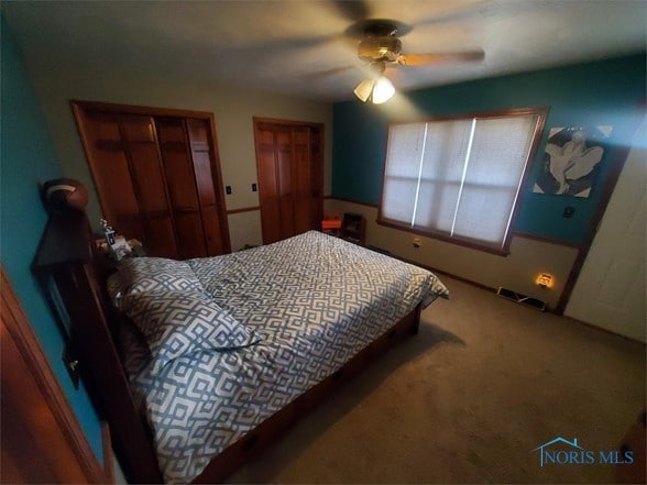 bedroom with carpet, two closets, and ceiling fan