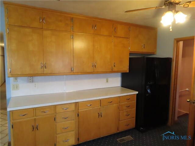 kitchen featuring black fridge with ice dispenser and ceiling fan