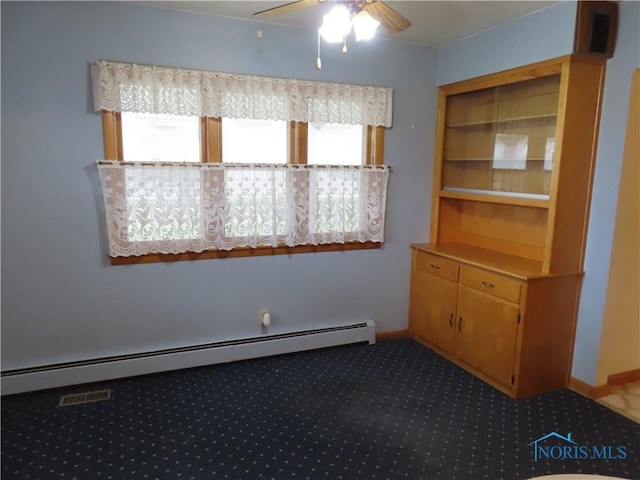 carpeted spare room featuring ceiling fan and a baseboard heating unit