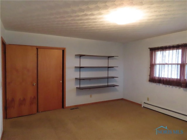 unfurnished bedroom featuring a baseboard radiator, a closet, and light colored carpet