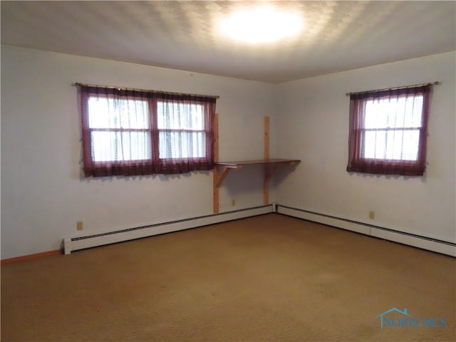 carpeted spare room with baseboard heating and plenty of natural light