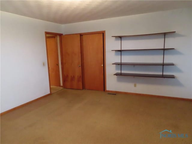 unfurnished bedroom featuring light carpet and a closet