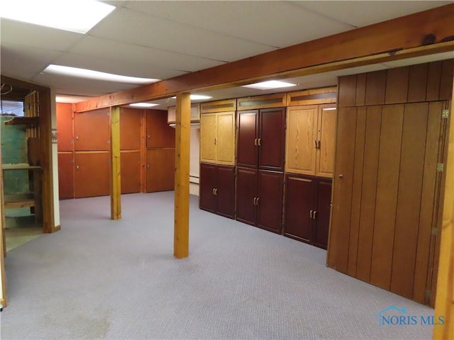 basement featuring a drop ceiling and light colored carpet