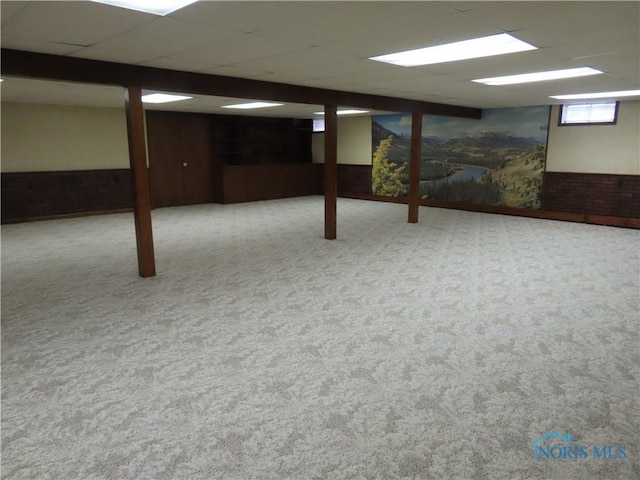 basement with light carpet and wood walls