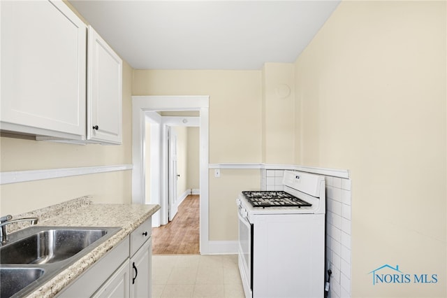 1919 Brookwood Ave, Toledo, OH 43604 - kitchen with white cabinetry, white gas stove, sink, light stone counters, and light hardwood / wood-style floors