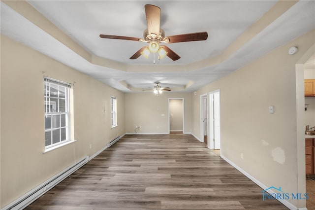 spare room with wood-type flooring, a raised ceiling, ceiling fan, and a baseboard heating unit