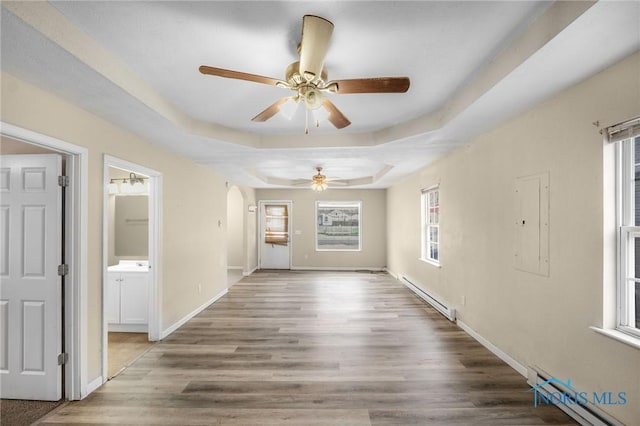 interior space featuring a tray ceiling, baseboard heating, ceiling fan, and hardwood / wood-style flooring