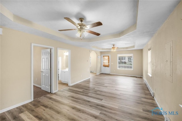 empty room featuring a raised ceiling, ceiling fan, and wood-type flooring