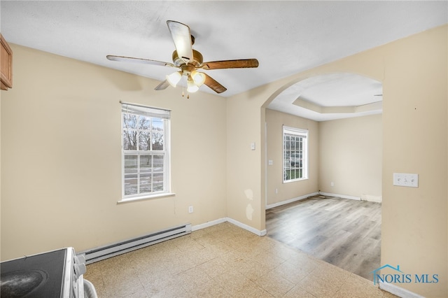 unfurnished room with ceiling fan, light hardwood / wood-style floors, a raised ceiling, and baseboard heating