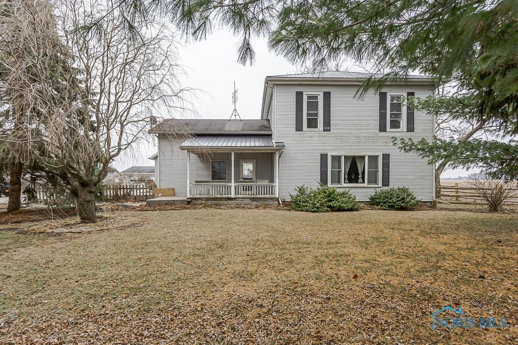 rear view of house featuring a porch and a lawn