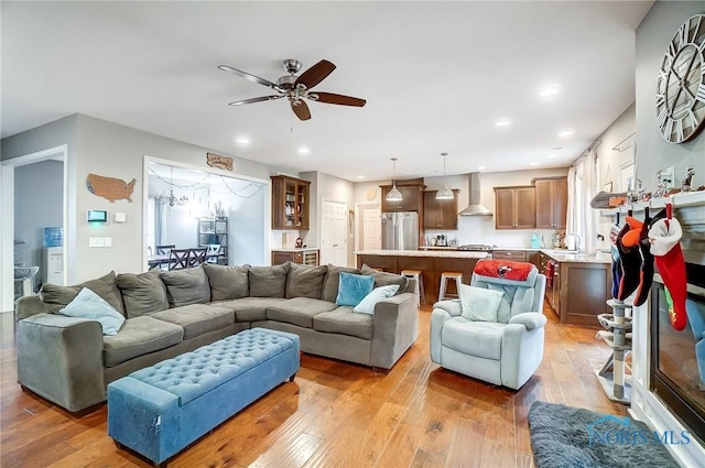 living room with ceiling fan, light hardwood / wood-style floors, and sink