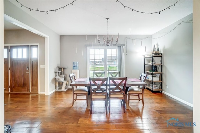 dining space with hardwood / wood-style floors, a healthy amount of sunlight, and a chandelier