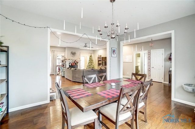 dining room featuring ceiling fan with notable chandelier and hardwood / wood-style flooring