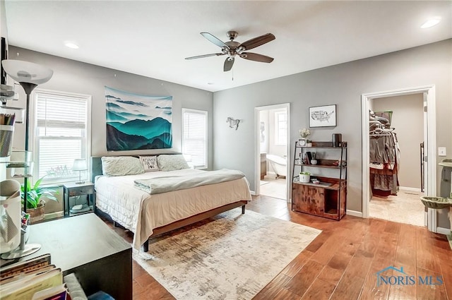 bedroom with ensuite bath, ceiling fan, light hardwood / wood-style floors, a walk in closet, and a closet