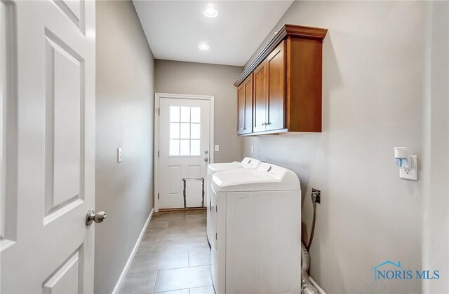 laundry room featuring cabinets, light tile patterned flooring, and washing machine and clothes dryer