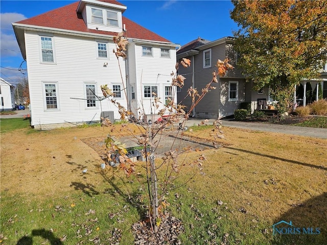 back of house featuring central AC and a lawn