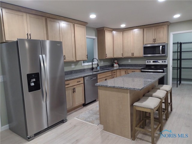 kitchen featuring sink, a kitchen island, stainless steel appliances, and light hardwood / wood-style floors