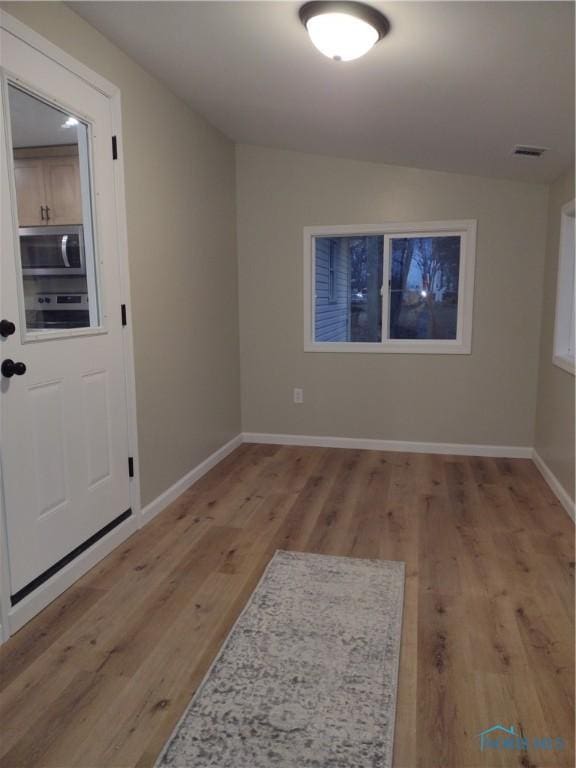 spare room featuring light hardwood / wood-style floors and vaulted ceiling