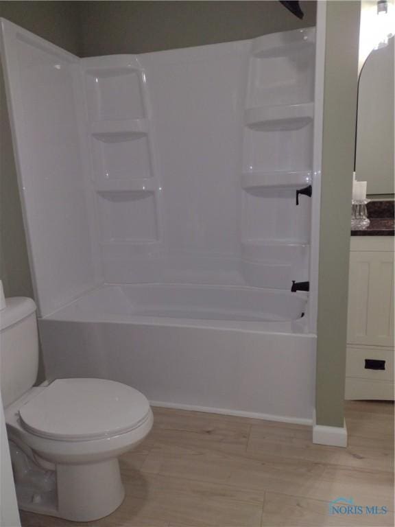 full bathroom with wood-type flooring, vanity, bathing tub / shower combination, and toilet