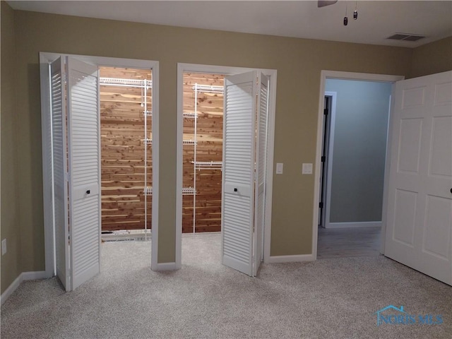 unfurnished bedroom featuring ceiling fan, light colored carpet, and wooden walls