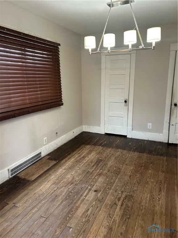 unfurnished dining area featuring hardwood / wood-style floors and a chandelier