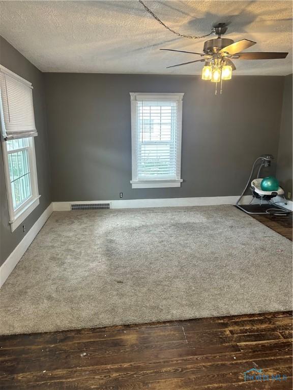 empty room featuring a textured ceiling, dark hardwood / wood-style floors, and ceiling fan