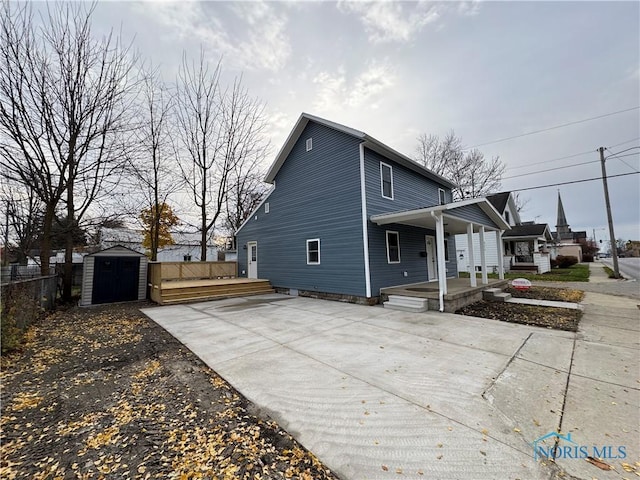 view of side of home featuring a porch and a storage shed