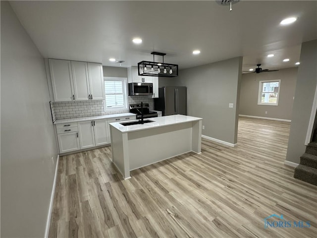 kitchen with stainless steel appliances, white cabinetry, a healthy amount of sunlight, and light hardwood / wood-style floors