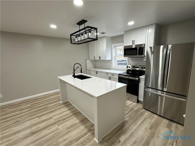 kitchen with sink, stainless steel appliances, an island with sink, white cabinets, and light wood-type flooring