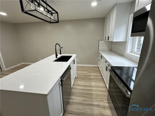 kitchen with white cabinets, sink, an island with sink, appliances with stainless steel finishes, and light hardwood / wood-style floors