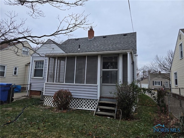 rear view of house featuring a lawn and a sunroom