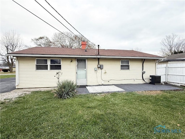 rear view of house with central AC unit, a patio area, and a lawn