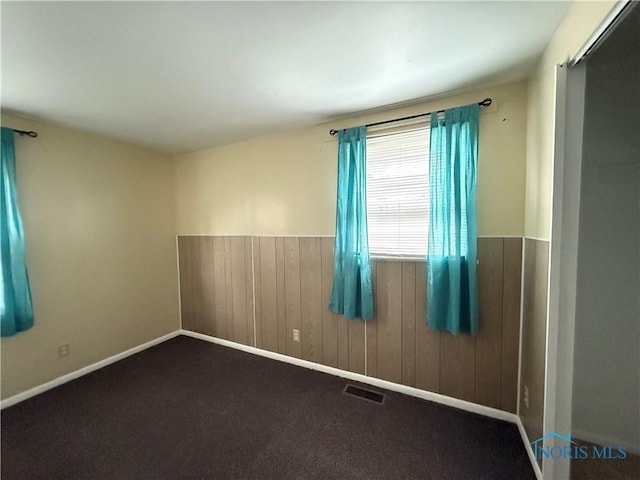 spare room featuring carpet floors and wood walls