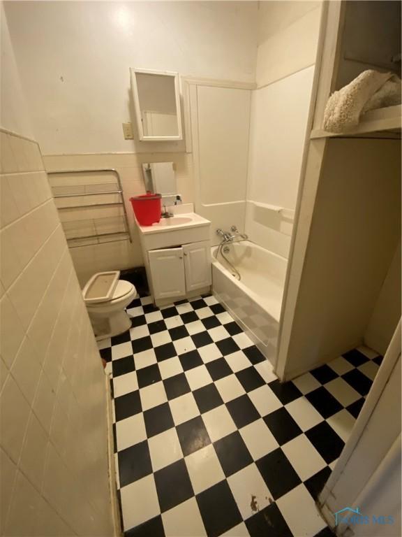 bathroom featuring vanity, toilet, tile walls, and a bathing tub