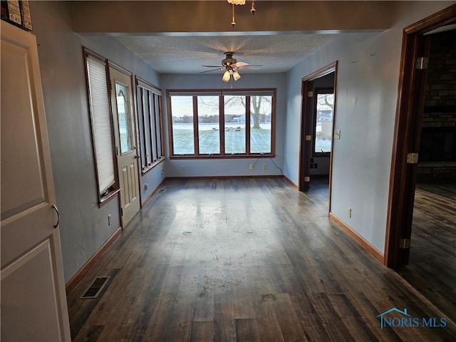 interior space featuring a textured ceiling, a water view, ceiling fan, and dark wood-type flooring