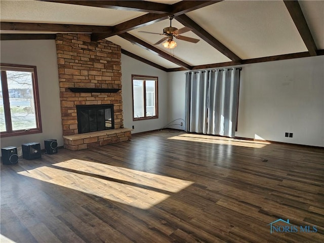 unfurnished living room featuring wood-type flooring, vaulted ceiling with beams, a stone fireplace, and plenty of natural light