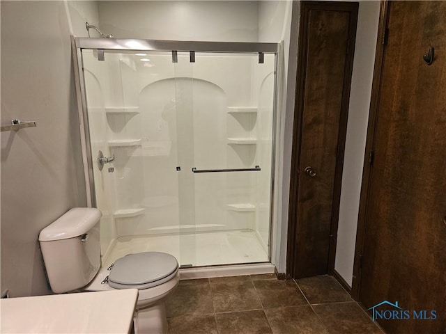 bathroom featuring tile patterned floors, toilet, and walk in shower