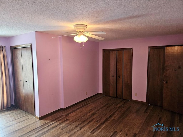 unfurnished bedroom featuring multiple closets, ceiling fan, hardwood / wood-style floors, and a textured ceiling