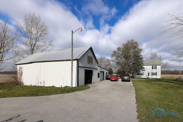 view of side of home featuring a lawn, an outbuilding, and a garage