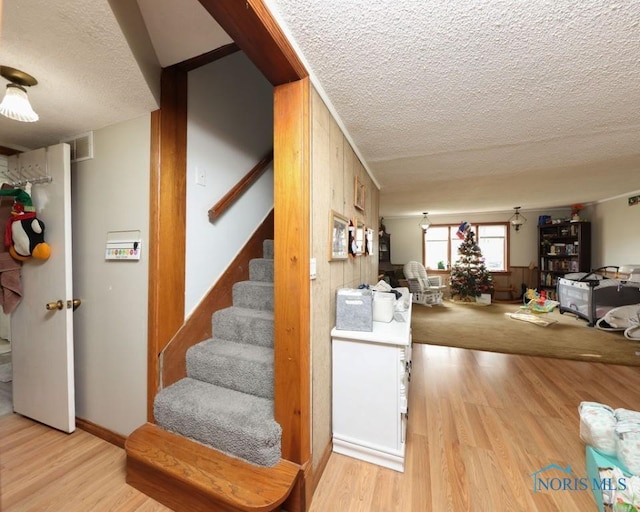 stairs with wood-type flooring, a textured ceiling, and wood walls